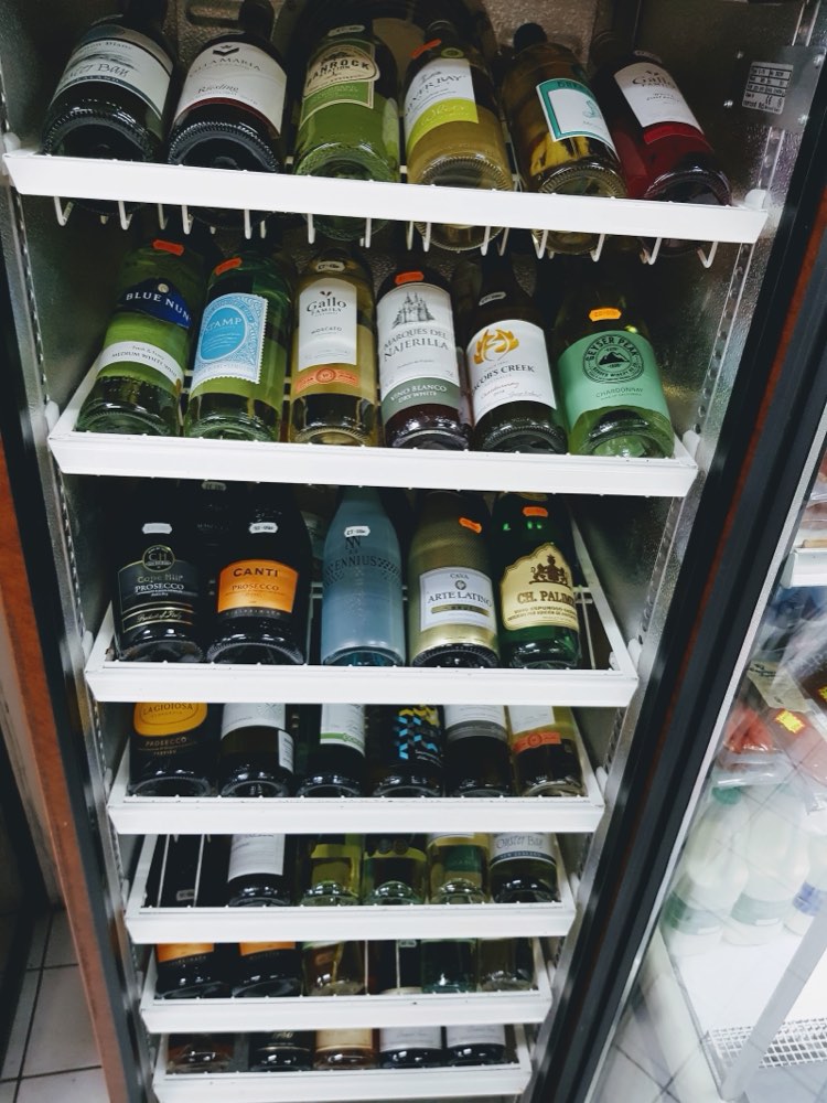 Chilled white wine, prosecco and cava in the fridge at Barry's Food & Wine, ready to take away